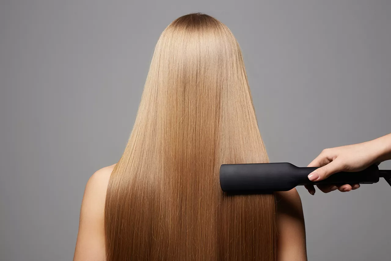 beautiful blond hair woman. Back of girl with Healthy hair. Care and straightening hair with an iron