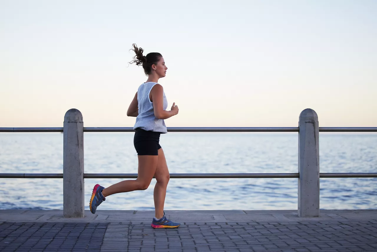Shot of a sporty young woman out for a run on the promenade.