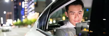 asian successful businessman use smart phone in the car at night