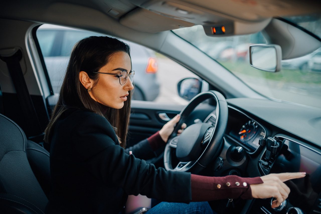 Businesswoman driving modern car and using navigation system