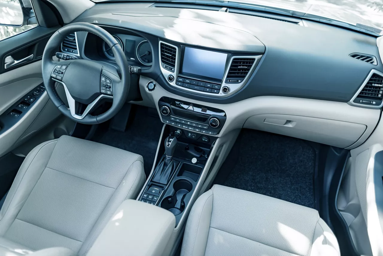 Luxury car interior shows steering wheel, shift lever and dashboard.