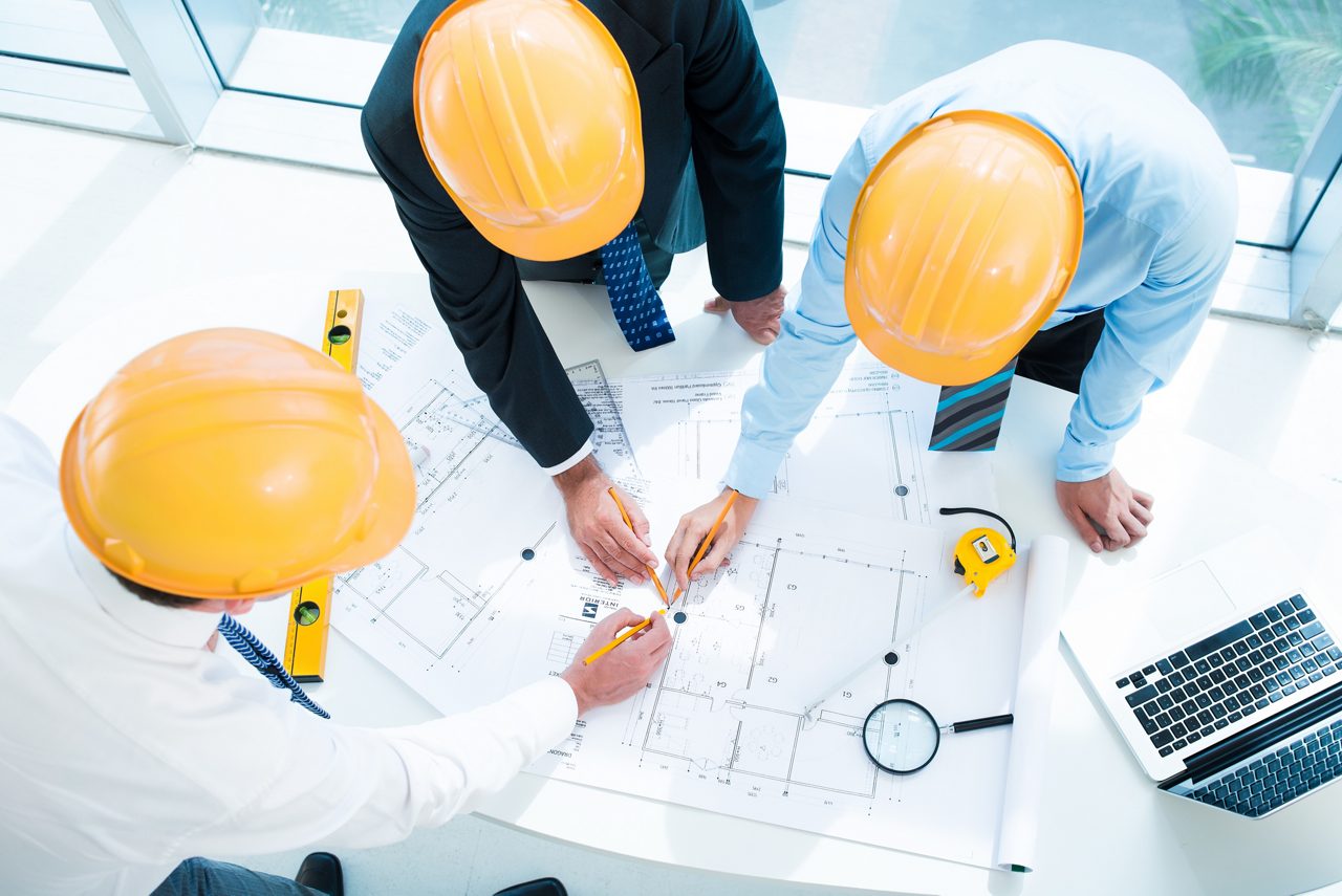 Three employees looking at blueprints and schematics