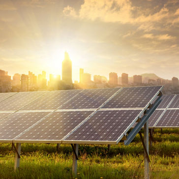 paneles solares y generadores eólicos contra la vista de la ciudad al atardecer