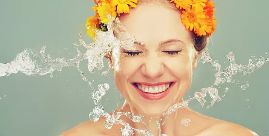 mulher sorrindo com flores amarela na cabeça, flexe de água lavando seu rosto