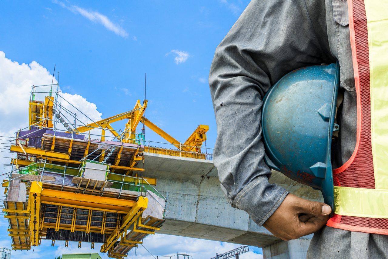 Construction worker checking location site with crane in the background 