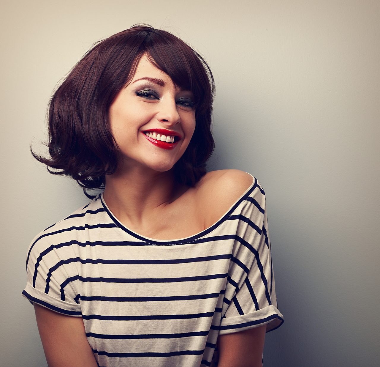Primer plano de una mujer joven con cabello corto en una blusa de moda y maquillaje