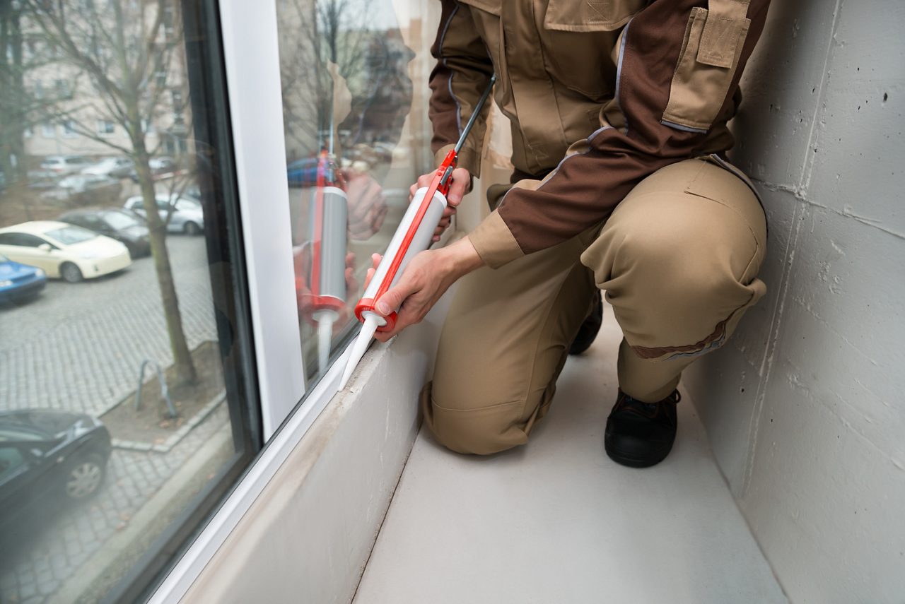 Um homem calafetando uma nova moldura de janela