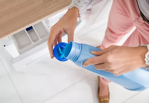 Close-up of female hands pouring detergent in the blue bottle cap