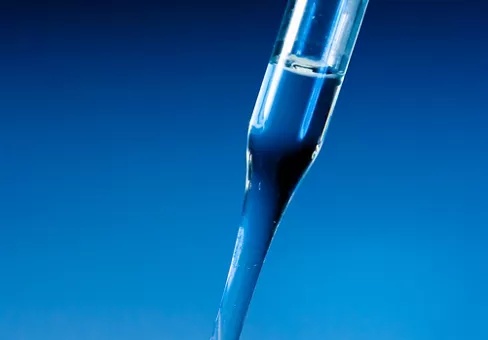 Glass dropper drips clear liquid into petri dish