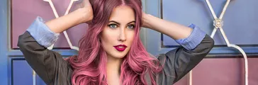 Beautiful hipster fashion model with curly pink hair posing in front of the colorful wall