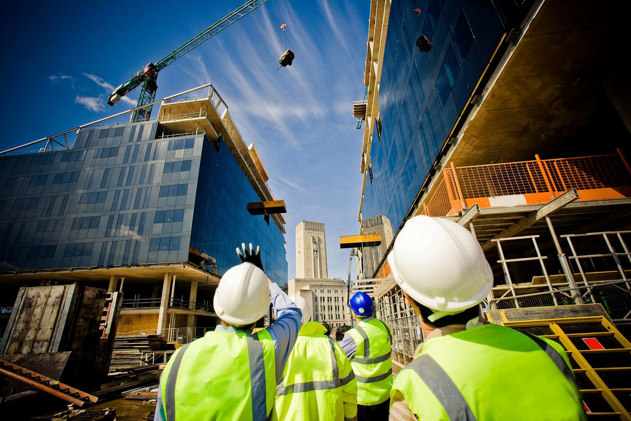 Construction workers looking up at buildings with paper and pencil sketch