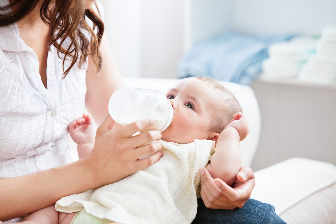 Mother feeding infant from baby bottle