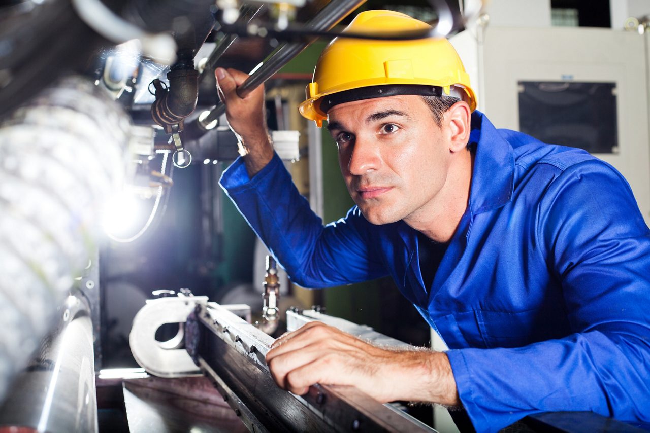 Modern industrial machine operator working in factory